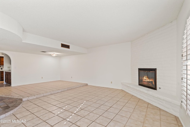 unfurnished living room with light tile patterned floors and a fireplace