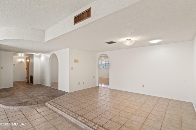 empty room featuring a textured ceiling and light tile patterned floors