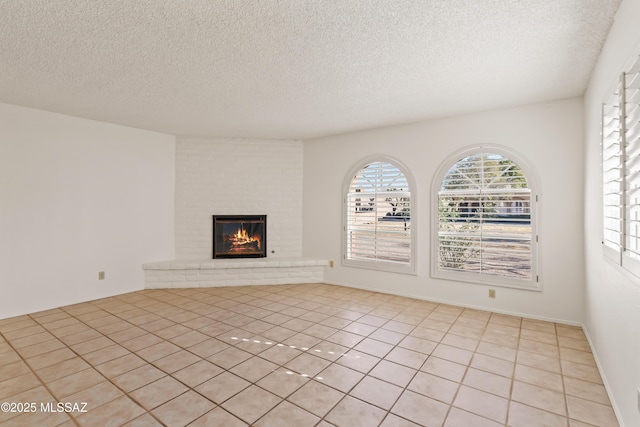 unfurnished living room with a fireplace, a textured ceiling, and light tile patterned floors