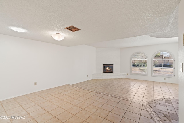 unfurnished living room featuring a large fireplace, a textured ceiling, and light tile patterned floors