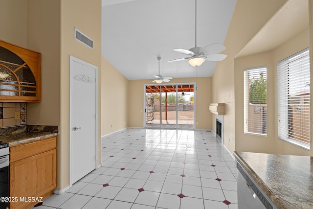 kitchen featuring light tile patterned flooring, stainless steel dishwasher, vaulted ceiling, and a large fireplace