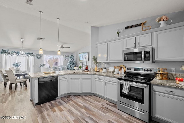 kitchen with decorative light fixtures, white cabinetry, stainless steel appliances, and vaulted ceiling