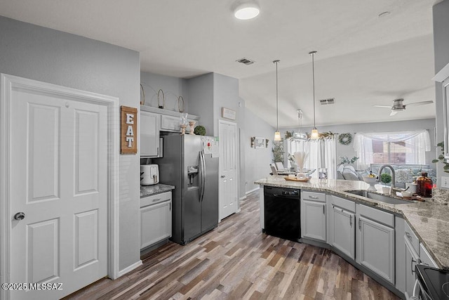 kitchen featuring appliances with stainless steel finishes, lofted ceiling, sink, hanging light fixtures, and light stone counters