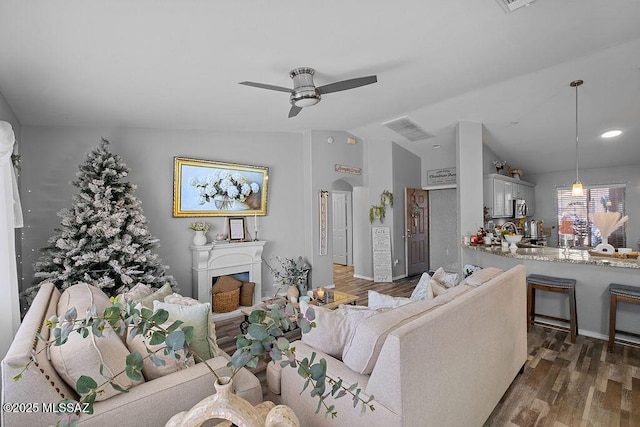 living room with vaulted ceiling, ceiling fan, and dark wood-type flooring