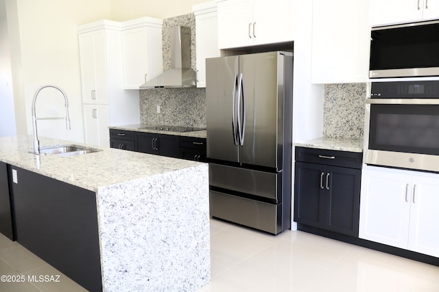 kitchen with wall chimney range hood, white cabinetry, stainless steel appliances, and a sink