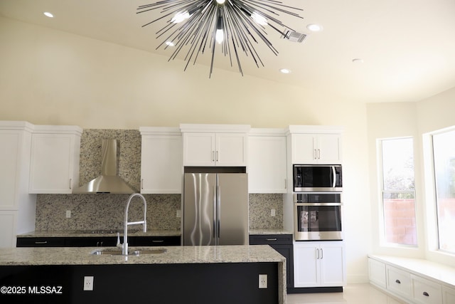 kitchen featuring stainless steel appliances, white cabinets, wall chimney range hood, and light stone countertops