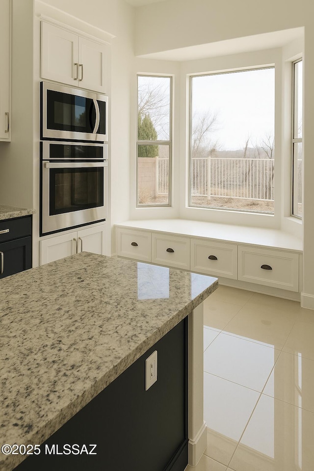 57 Highland Cir, Rio Rico, AZ 85648 - kitchen featuring appliances with stainless steel finishes, light stone counters, light tile patterned flooring, and white cabinetry