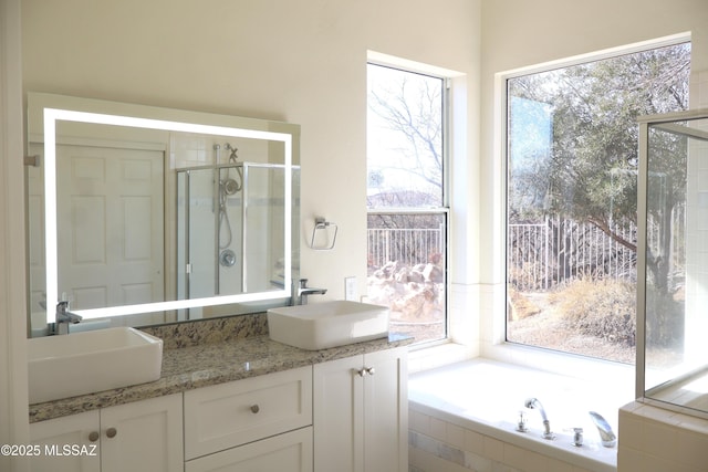 full bathroom featuring a garden tub, double vanity, a sink, and a shower stall