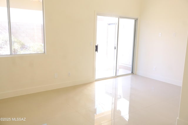 empty room featuring baseboards and light tile patterned floors