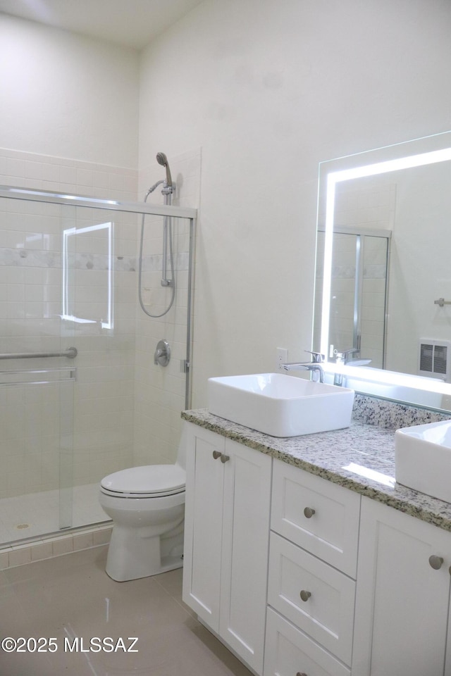 full bath with a stall shower, a sink, toilet, and double vanity