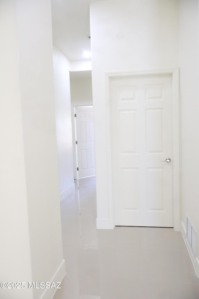 hall featuring light tile patterned floors, baseboards, and visible vents