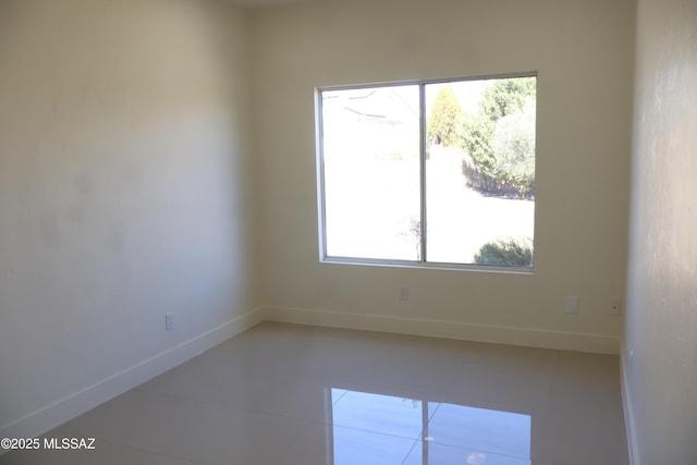 empty room featuring baseboards and tile patterned floors