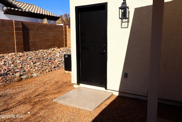 doorway to property featuring fence and stucco siding