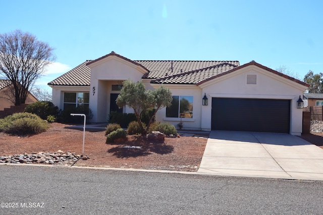 mediterranean / spanish house with an attached garage, driveway, a tiled roof, and stucco siding