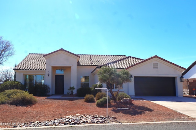 mediterranean / spanish house featuring a tile roof, driveway, an attached garage, and stucco siding