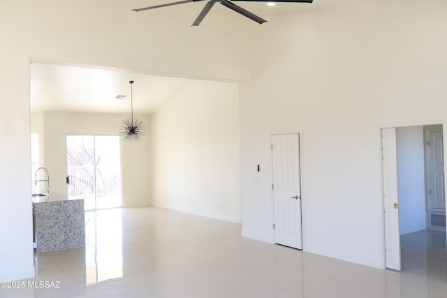 spare room with a ceiling fan, a sink, a towering ceiling, and baseboards