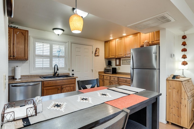 kitchen with sink, decorative backsplash, hanging light fixtures, and stainless steel appliances