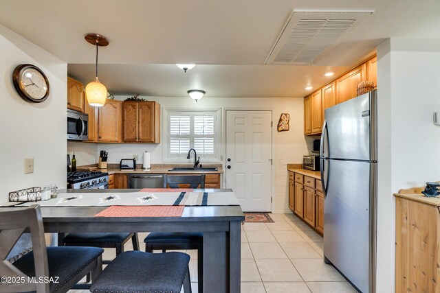 kitchen featuring pendant lighting, appliances with stainless steel finishes, sink, kitchen peninsula, and light tile patterned flooring