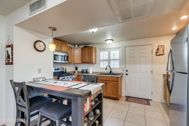 kitchen featuring decorative light fixtures, stainless steel appliances, sink, kitchen peninsula, and light tile patterned floors