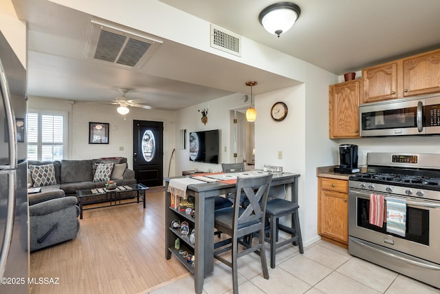 kitchen with light wood-type flooring, stainless steel appliances, ceiling fan, and pendant lighting