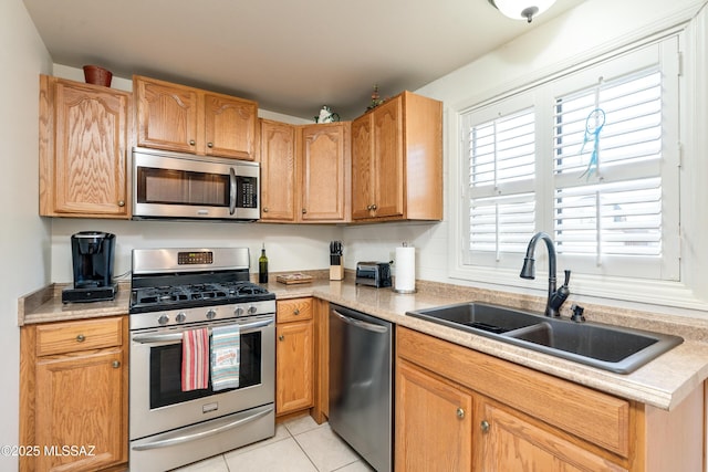 kitchen with sink, light tile patterned floors, and appliances with stainless steel finishes