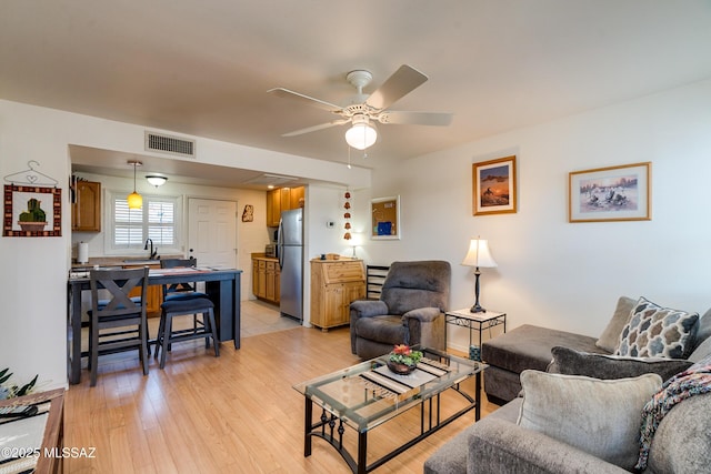 living room with ceiling fan, sink, and light hardwood / wood-style flooring