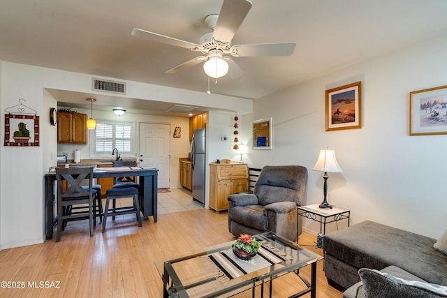 living room with ceiling fan, sink, and light hardwood / wood-style flooring