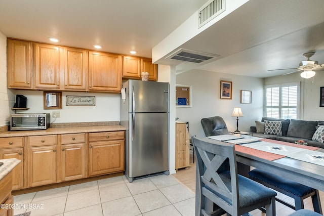 kitchen with light tile patterned floors, ceiling fan, and stainless steel refrigerator