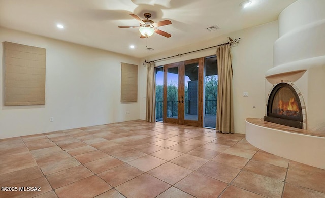 unfurnished living room featuring a ceiling fan, recessed lighting, light tile patterned floors, and a glass covered fireplace