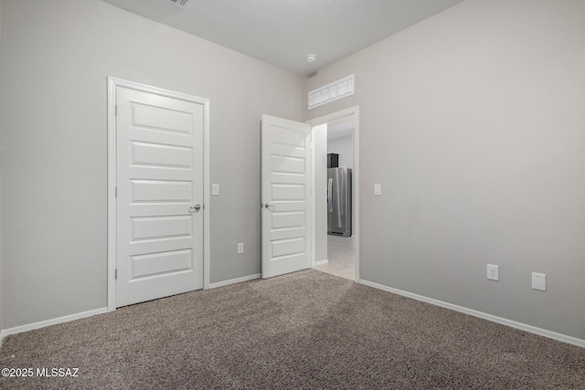 unfurnished bedroom featuring carpet, stainless steel refrigerator, and a closet