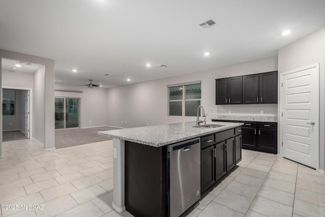 kitchen featuring light stone counters, a kitchen island with sink, dishwasher, and sink