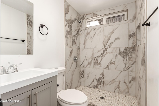 bathroom with vanity, toilet, and tiled shower