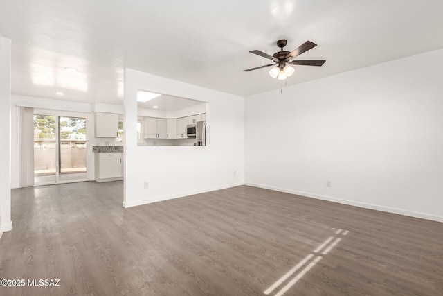 unfurnished living room with dark wood-type flooring and ceiling fan