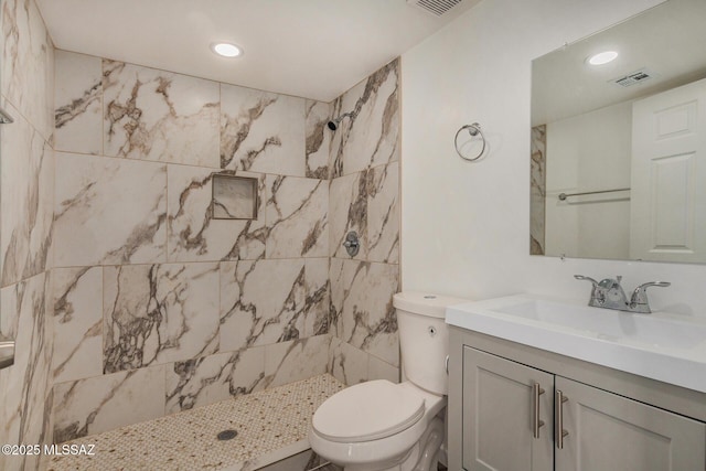 bathroom with vanity, toilet, and a tile shower