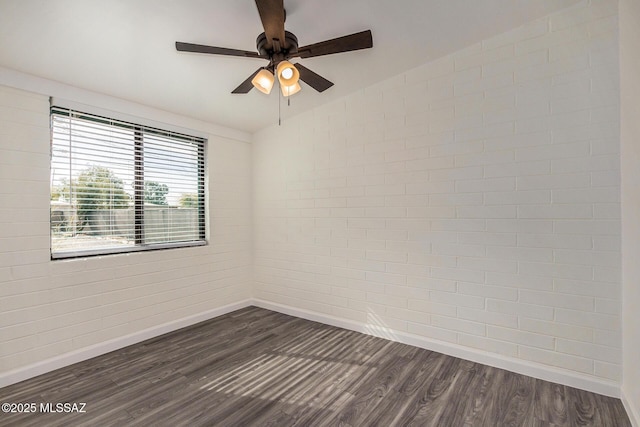 spare room featuring ceiling fan, dark wood-type flooring, vaulted ceiling, and brick wall