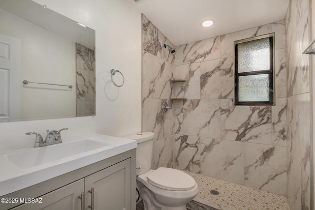 bathroom with tiled shower, vanity, and toilet