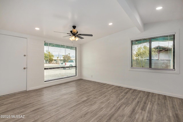 empty room with beamed ceiling, hardwood / wood-style flooring, and ceiling fan