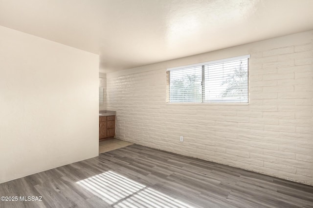 empty room featuring wood-type flooring and brick wall