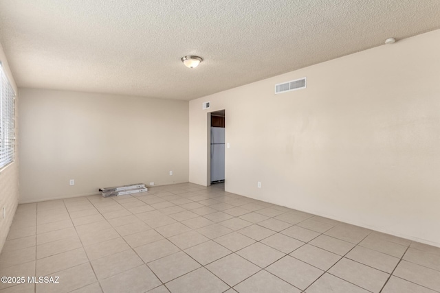 empty room featuring a textured ceiling and light tile patterned floors