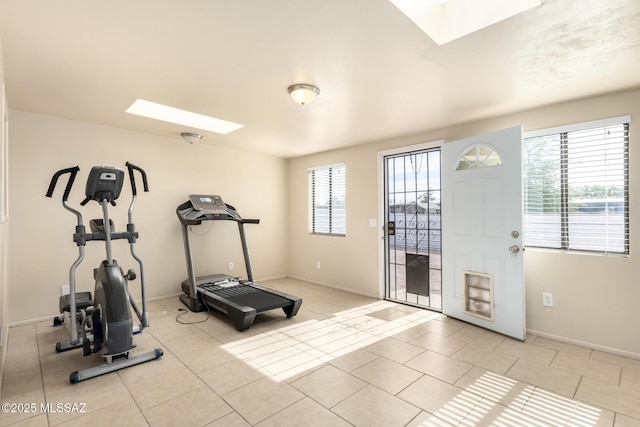 exercise room with a healthy amount of sunlight, light tile patterned floors, and a skylight