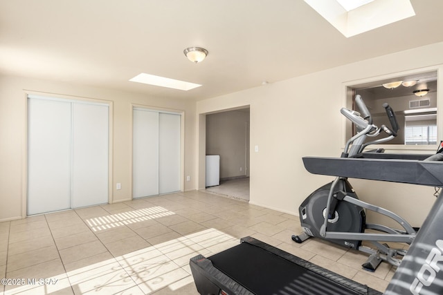 workout room with a skylight and light tile patterned flooring