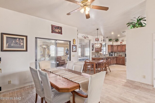 kitchen featuring light hardwood / wood-style floors, vaulted ceiling, tasteful backsplash, hanging light fixtures, and stainless steel appliances