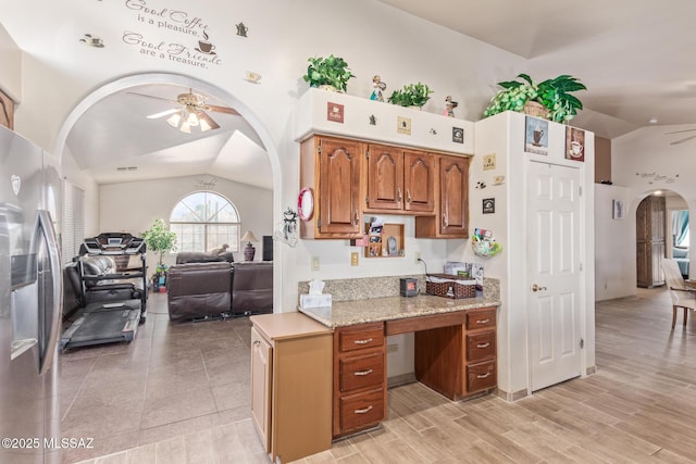 kitchen featuring appliances with stainless steel finishes, sink, light wood-type flooring, light stone counters, and lofted ceiling