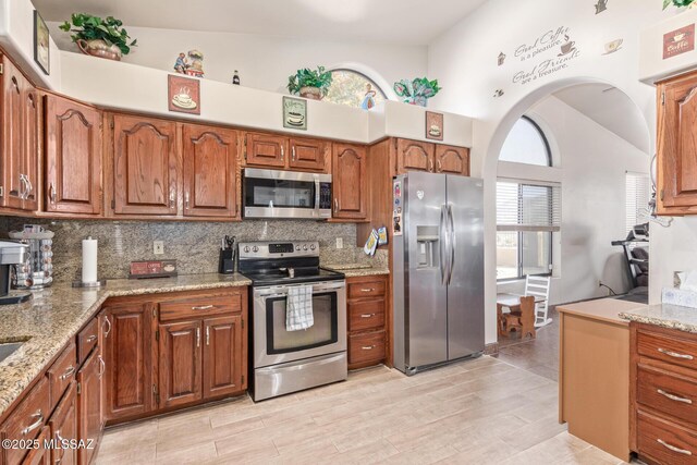 kitchen with light stone countertops, lofted ceiling, stainless steel refrigerator with ice dispenser, ceiling fan, and light hardwood / wood-style flooring