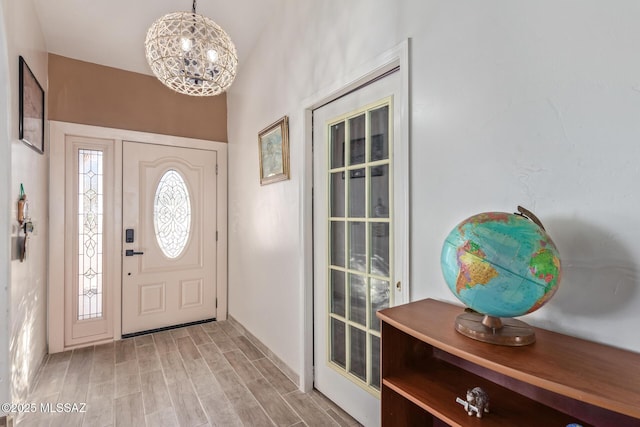 foyer entrance with plenty of natural light, light hardwood / wood-style flooring, and a notable chandelier