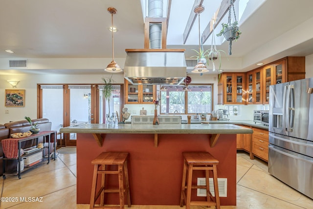 kitchen featuring light tile patterned floors, stainless steel fridge, a kitchen breakfast bar, and decorative light fixtures