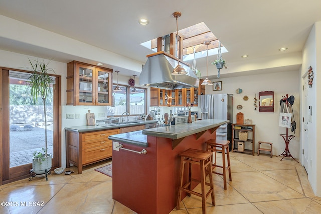 kitchen featuring light tile patterned floors, sink, stainless steel fridge, a kitchen island, and a kitchen bar