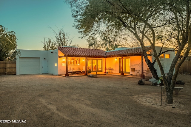 back house at dusk featuring a garage