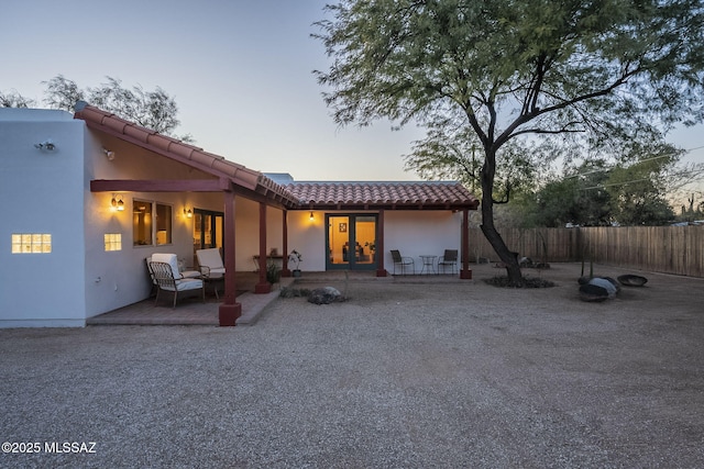 back house at dusk featuring a patio area