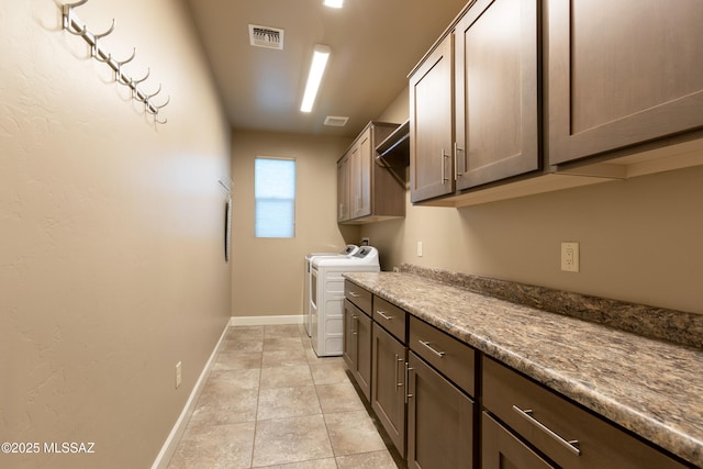 clothes washing area with cabinets, washer and dryer, and light tile patterned floors